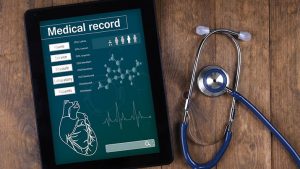 EHR Mandate depicted by Medical record on tablet screen with stethoscope on wooden background