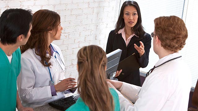 a healthcare informatics consultant speaking to a team of healthcare professionals in a conference room