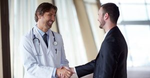 doctor handshake with a patient at doctors bright modern office in hospital