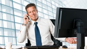 Successful businessman sit at his desk while talking on mobile in Successful businessman sit at his desk while talking on mobile in office.