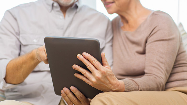 close up of happy senior couple with tablet looking at their patient portals at home
