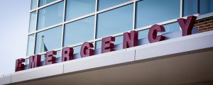 Emergency room entrance with red block letters on the metal awning of a hospital building