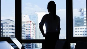 A woman looking over city skyline from office, she is in charge of healthcare technology