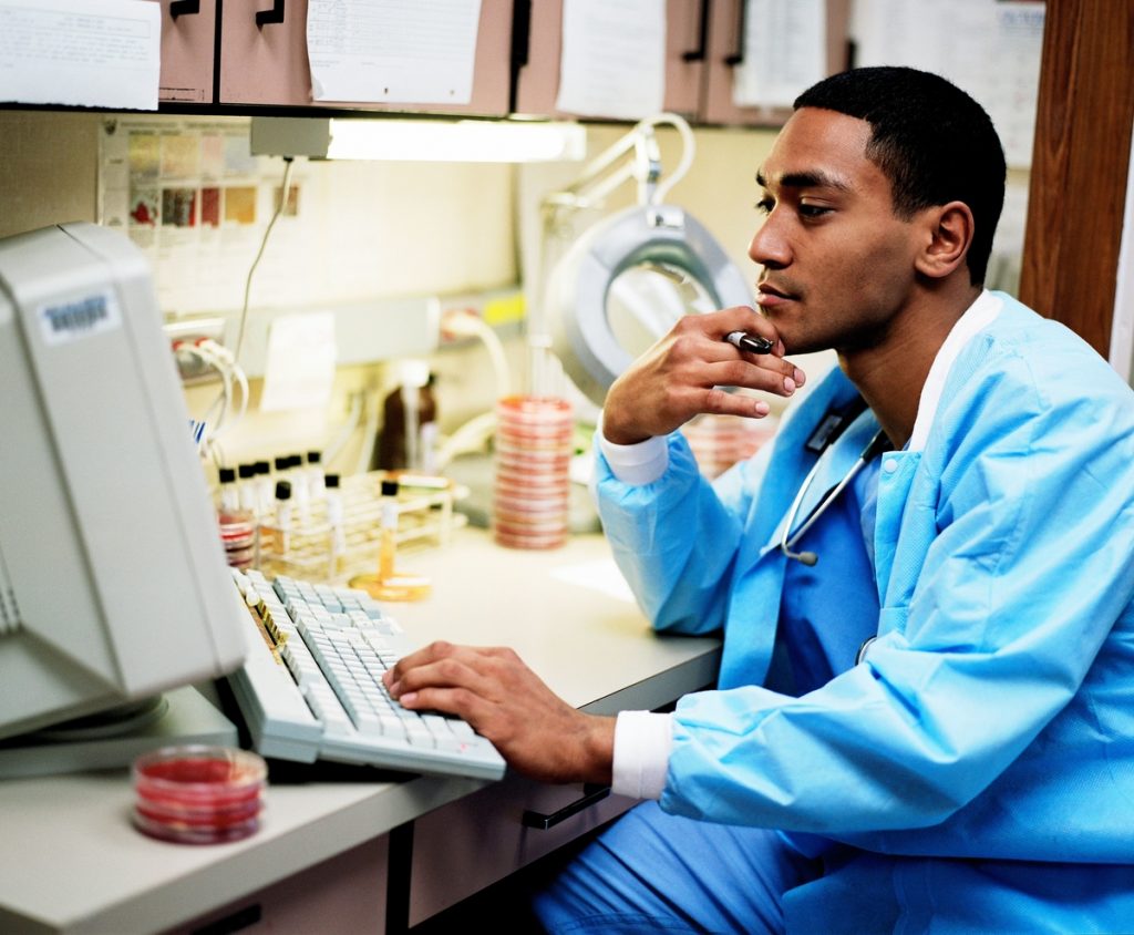young male doctor looking at a computer in a lab