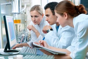 three healthcare professionals in a lab looking at a laptop