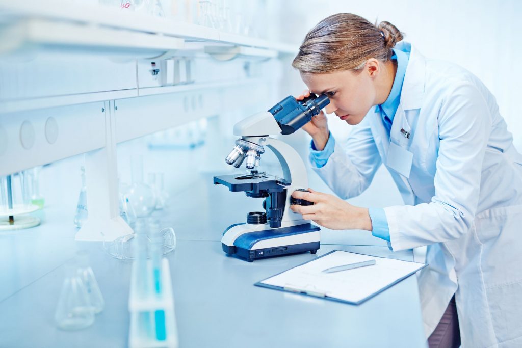 a female lab technician looking into a microscope