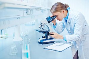 a female lab technician looking into a microscope