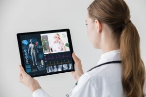 over the shoulder shot of female doctor participating in a telemedicine appointment on a tablet