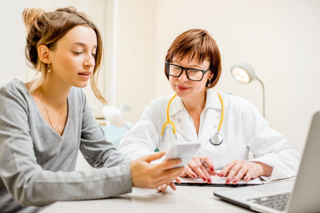 an older doctor with a younger woman they are both looking at the younger woman's smartphone