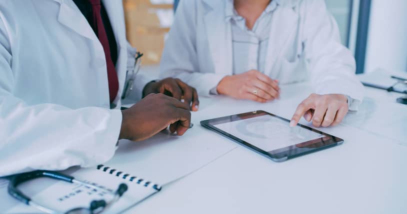 Two doctors using a tablet discussing a patient