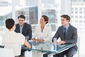 four people in suits sitting at a glass conference table