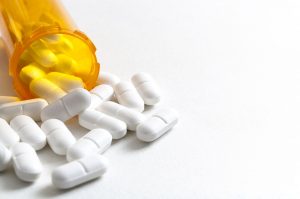 white pills spilling out of a prescription bottle