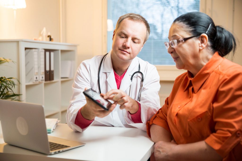 a male doctor with a tablet and an elderly woman looking at the tablet