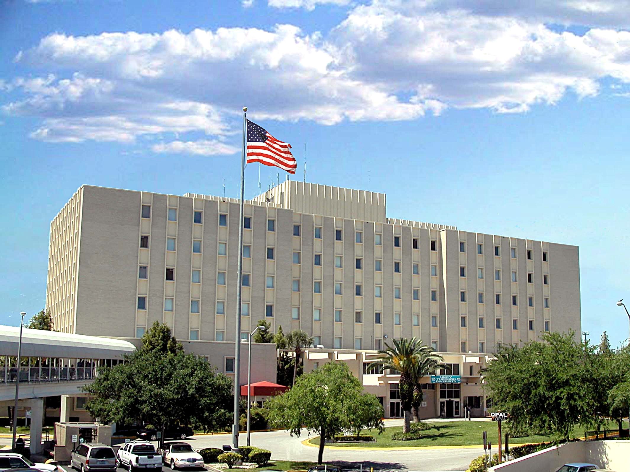 american flag with JAHVH hospital building in the background and clouds overhead in the daytime
