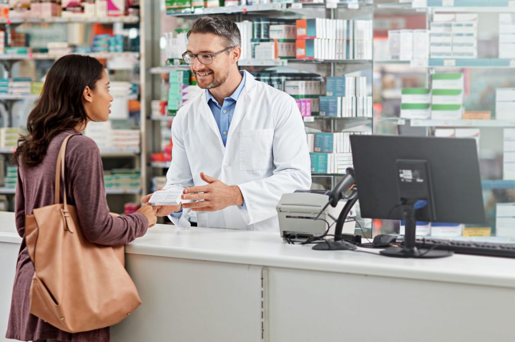 smiling male pharmacist consulting with a female patient at the pharmacy checkout