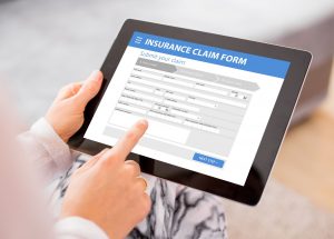 insurance claim form on a tablet with hands interacting with it
