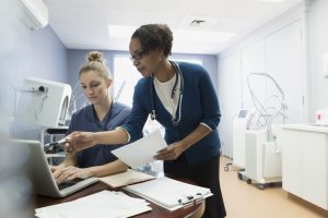 two medical professionals looking at a laptop in bright, cold examination room