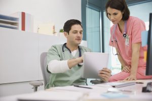 two healthcare professionals in an office looking at a tablet