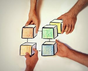 four hands holding cube-shped blocks colored in with crayon