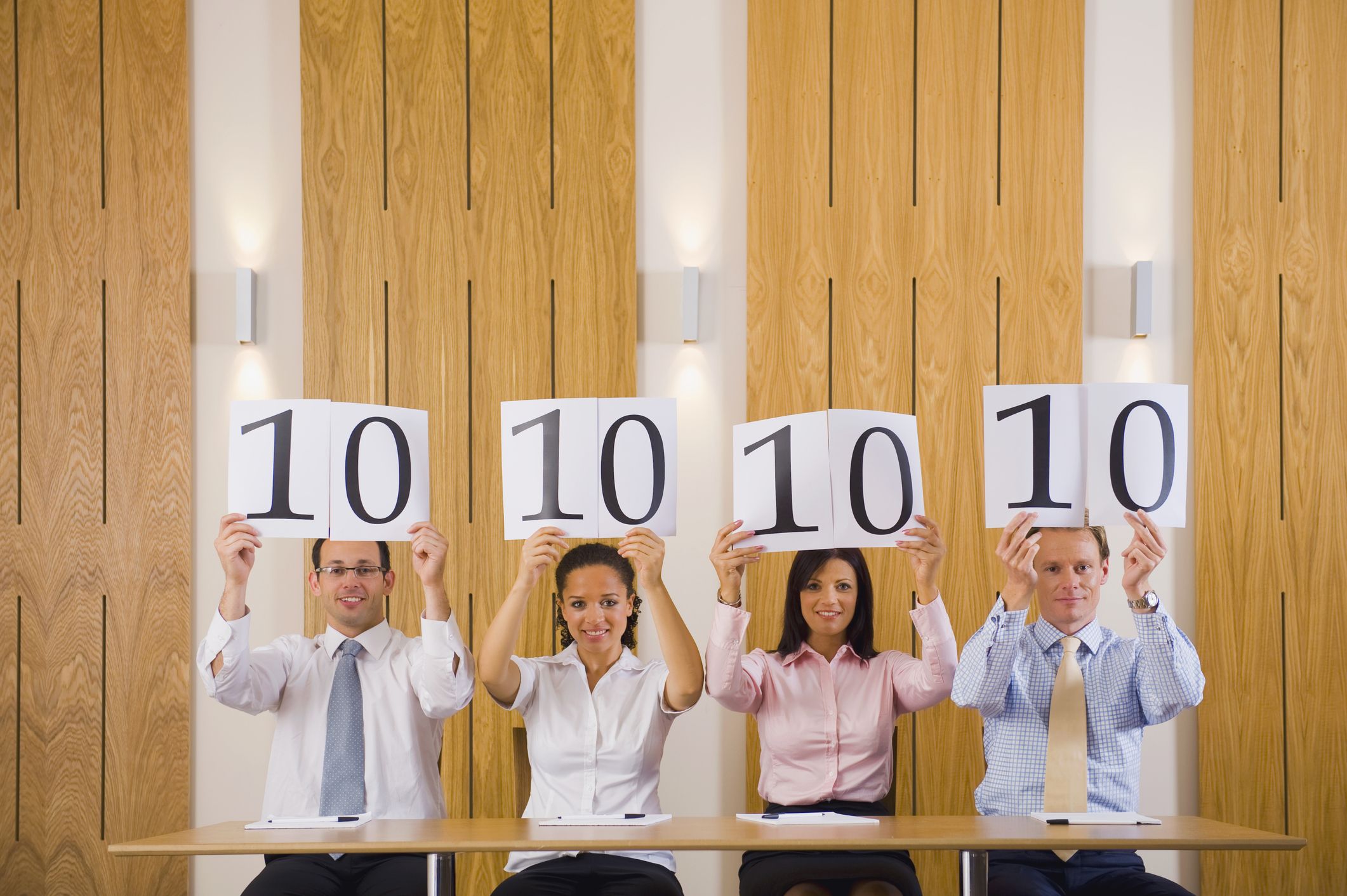 four people dressed in casual business attire, each holding up the number ten