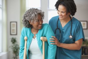 A nurse ensures a patient is stable as she tries to walk on crutches.