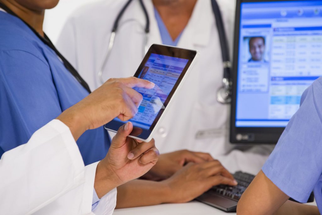 Doctors look at a patients EHR on a tablet.