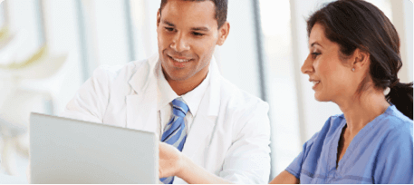 two healthcare professionals looking at electronic medical records and smiling signifying a certificate in health informatics