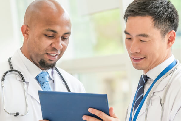 two doctors in a brightly lit atrium looking at a digital tablet