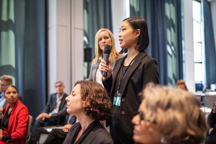 Healthcare professionals asking questions in a conference session.