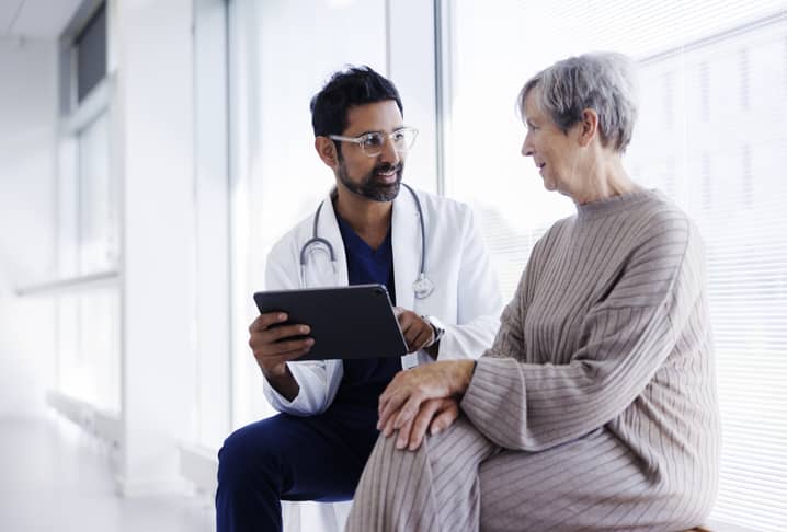 Male doctor and female patient discuss lab results shown on a tablet