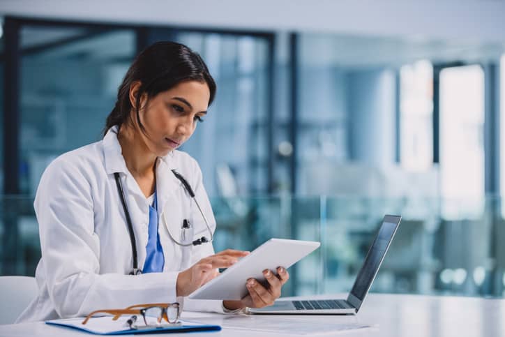 A young female healthcare professional uses a digital tablet.