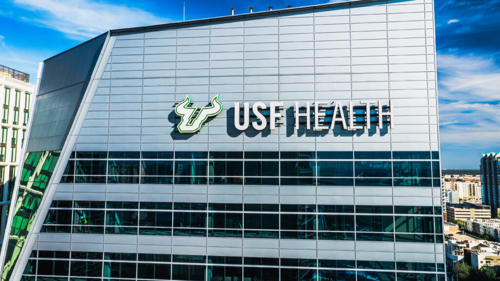 The USF Health building in Tampa, Florida, featuring a modern glass facade and the USF Health logo.