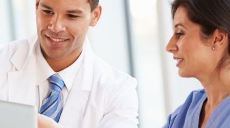 two healthcare professionals looking at electronic medical records and smiling signifying a certificate in health informatics